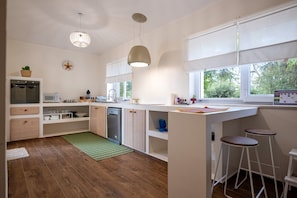 Une cuisine moderne avec des meubles en bois, un lave-vaisselle, un four à micro-ondes et une grande fenêtre.