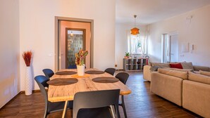 Un espacio habitable moderno con comedor, sofá y cocina al fondo.