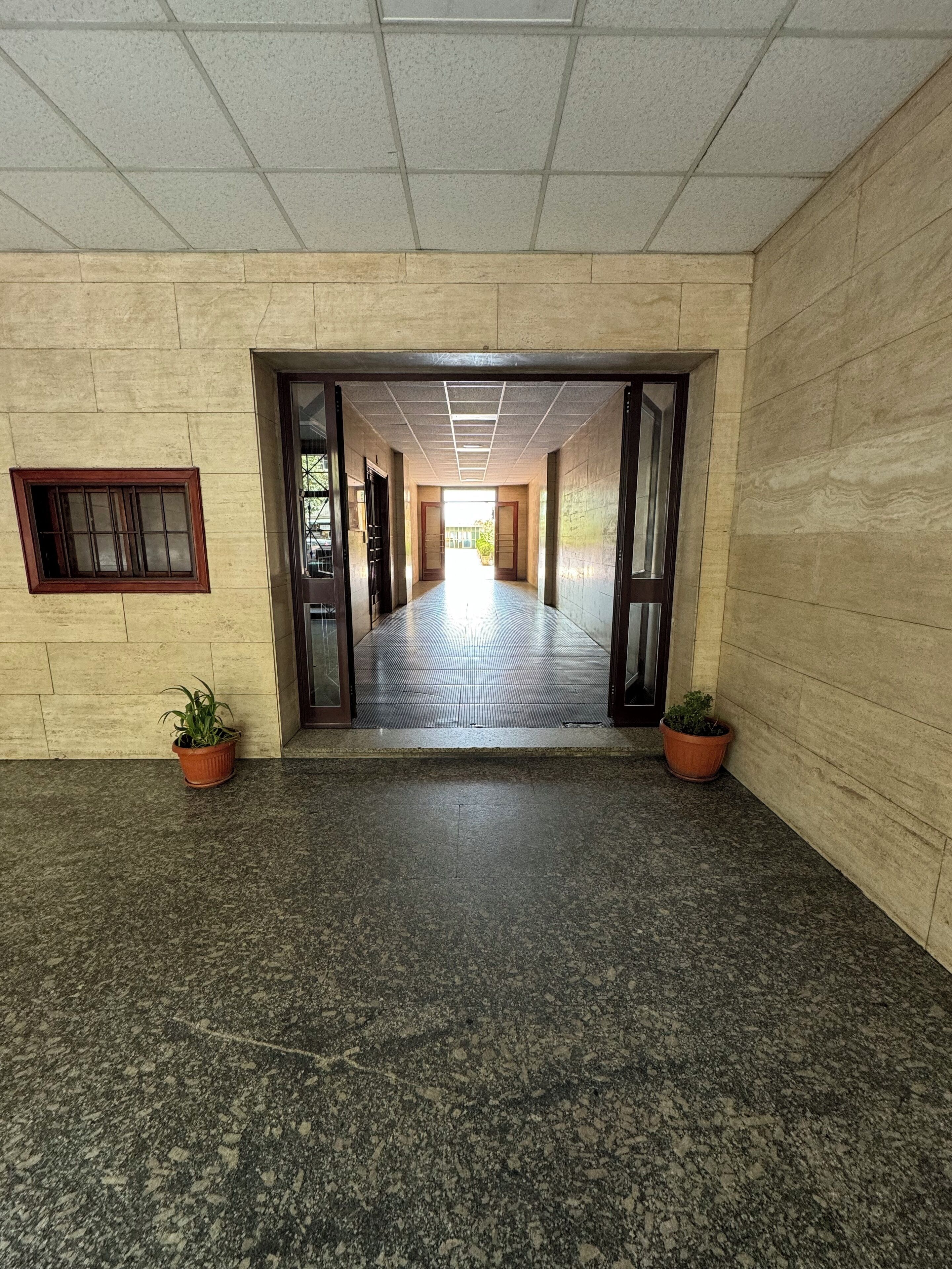 A corridor with a tiled floor leading to a bright exit.