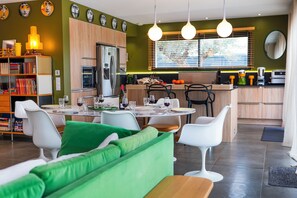 A modern kitchen with a dining area, featuring a central island, white chairs, and a green sofa. - Luxury Villa with Heated Pool - 6 Pers - Saleilles, near beaches (saleilles)