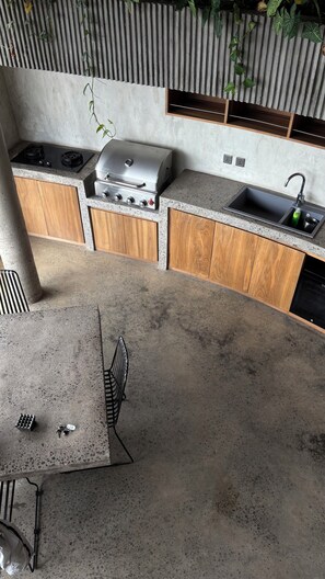A kitchen with a gas stove, grill, and sink. - Uluwatu Sea View Wellness Villa – 2BR w/ Sauna & Cold Plunge (Pecatu)