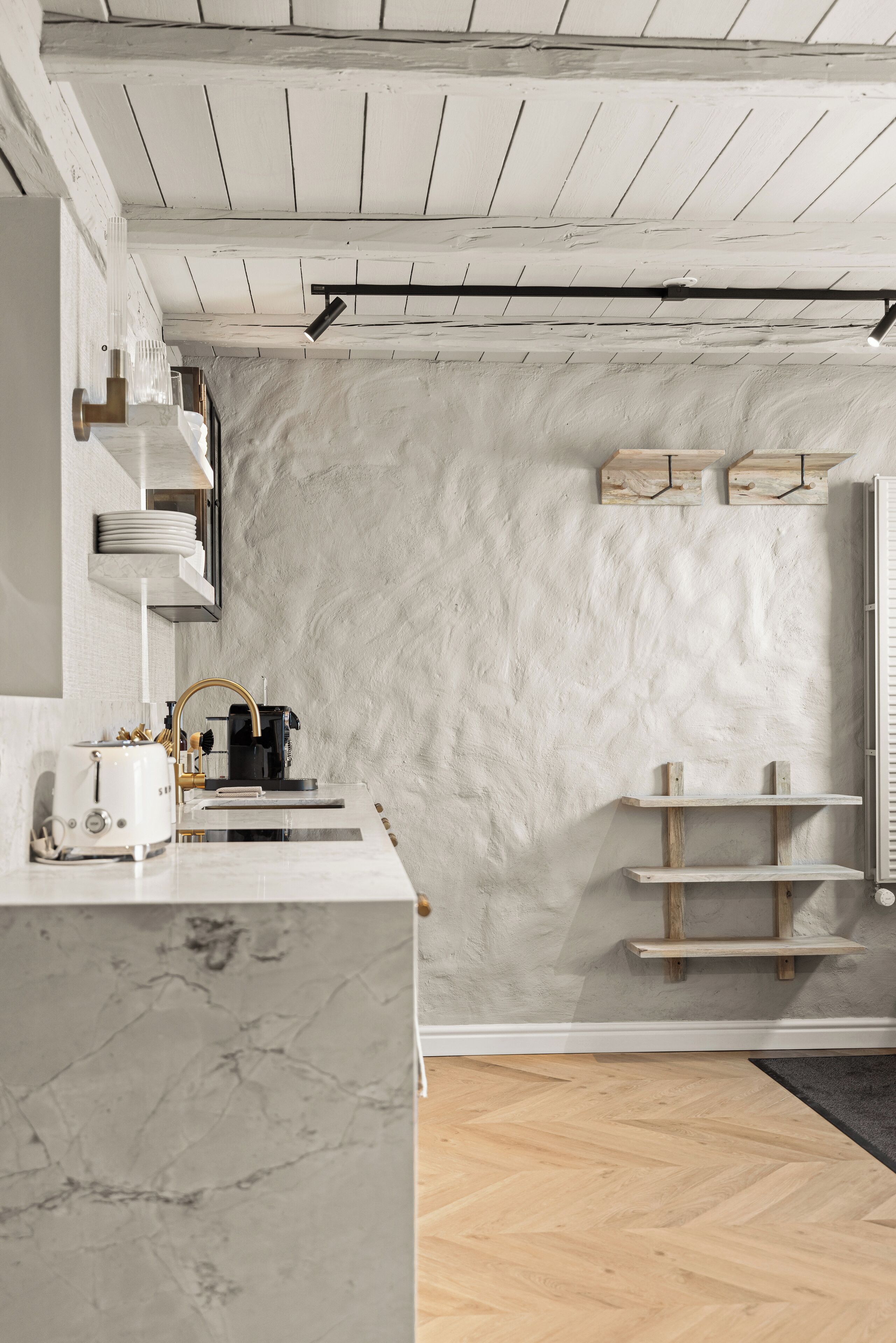 A modern kitchen with white cabinetry, a marble countertop, and wooden shelves.