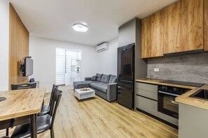 A modern kitchen with a built-in oven, a refrigerator, and wooden cabinets. - City Center Apartment | Cozy 1BR with Patio by PikHost (Tiranë)