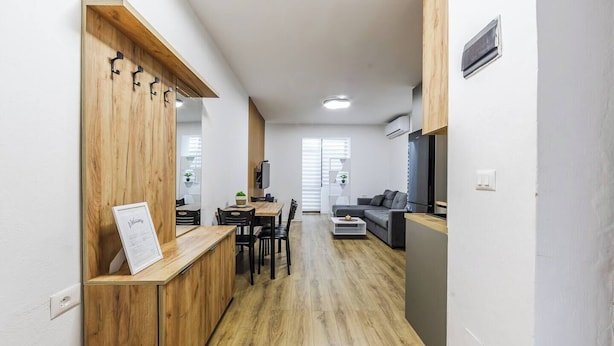 Un apartamento moderno con zona de comedor de madera, un sofá y una cocina.