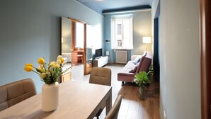 A modern living room with a dining area, a sofa, and a TV. - Charming Apartment in the Historic Center (Lucca)