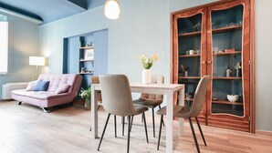 A modern living room with a sofa, dining table, chairs, and a cabinet. - Charming Apartment in the Historic Center (Lucca)