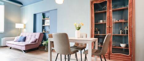 A modern living room with a sofa, dining table, chairs, and a cabinet.