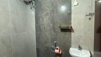 Un baño con inodoro, lavabo, ducha y un balde.
