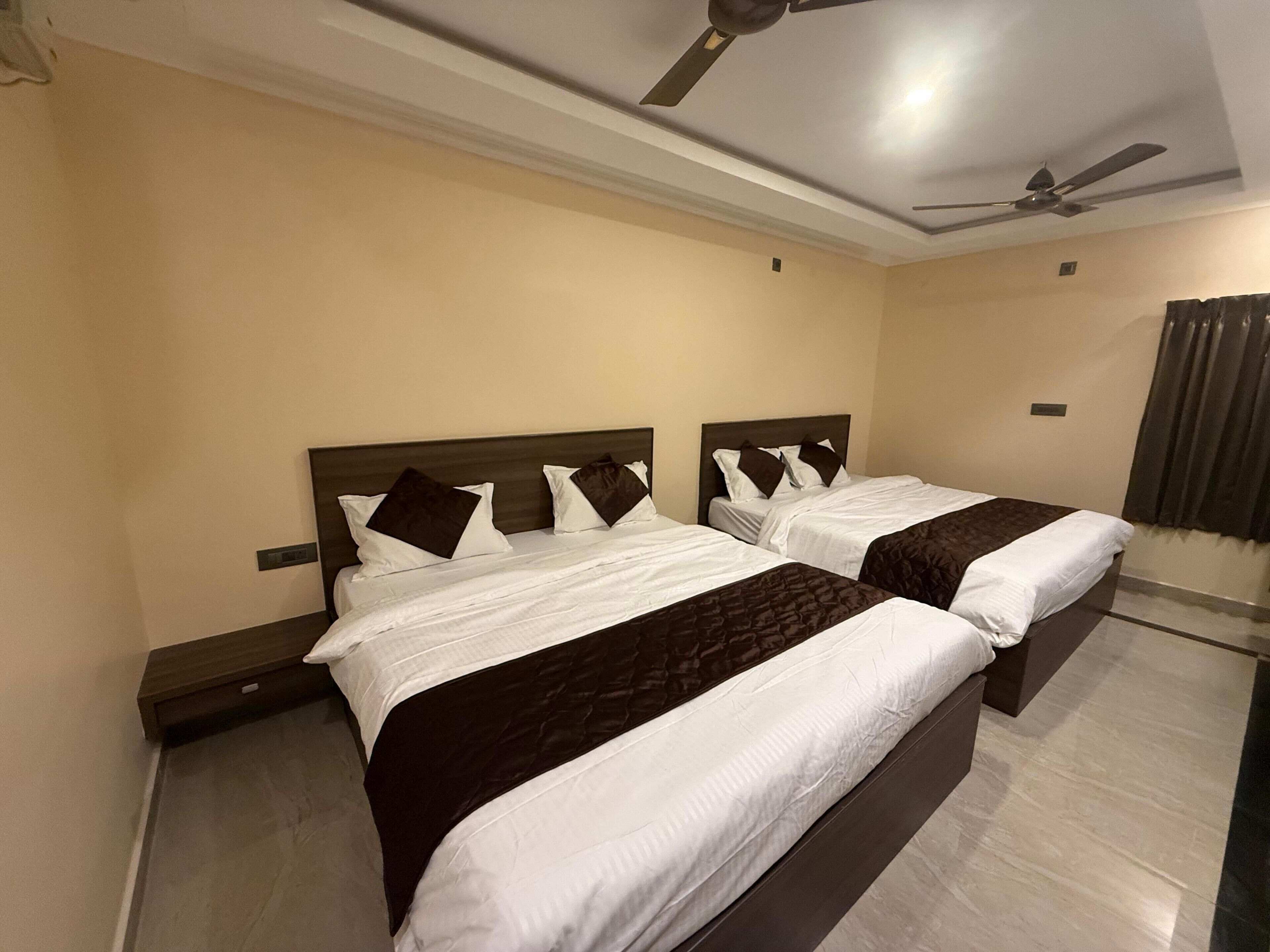 A hotel room with two beds, a ceiling fan, and a window with curtains.