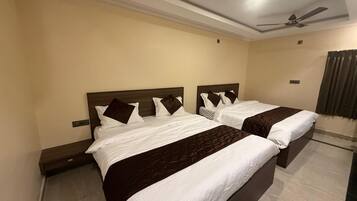 A hotel room with two beds, a ceiling fan, and a window with curtains.
