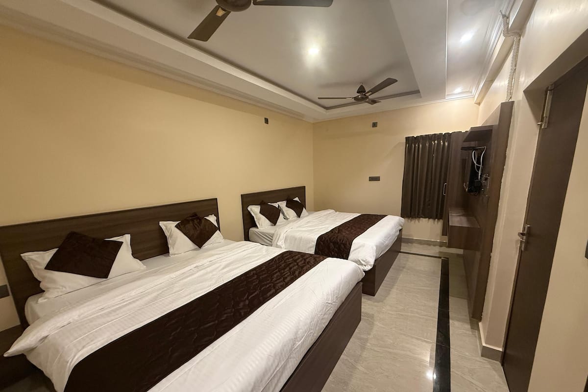 A hotel room with two beds, a ceiling fan, and a door leading to another room.