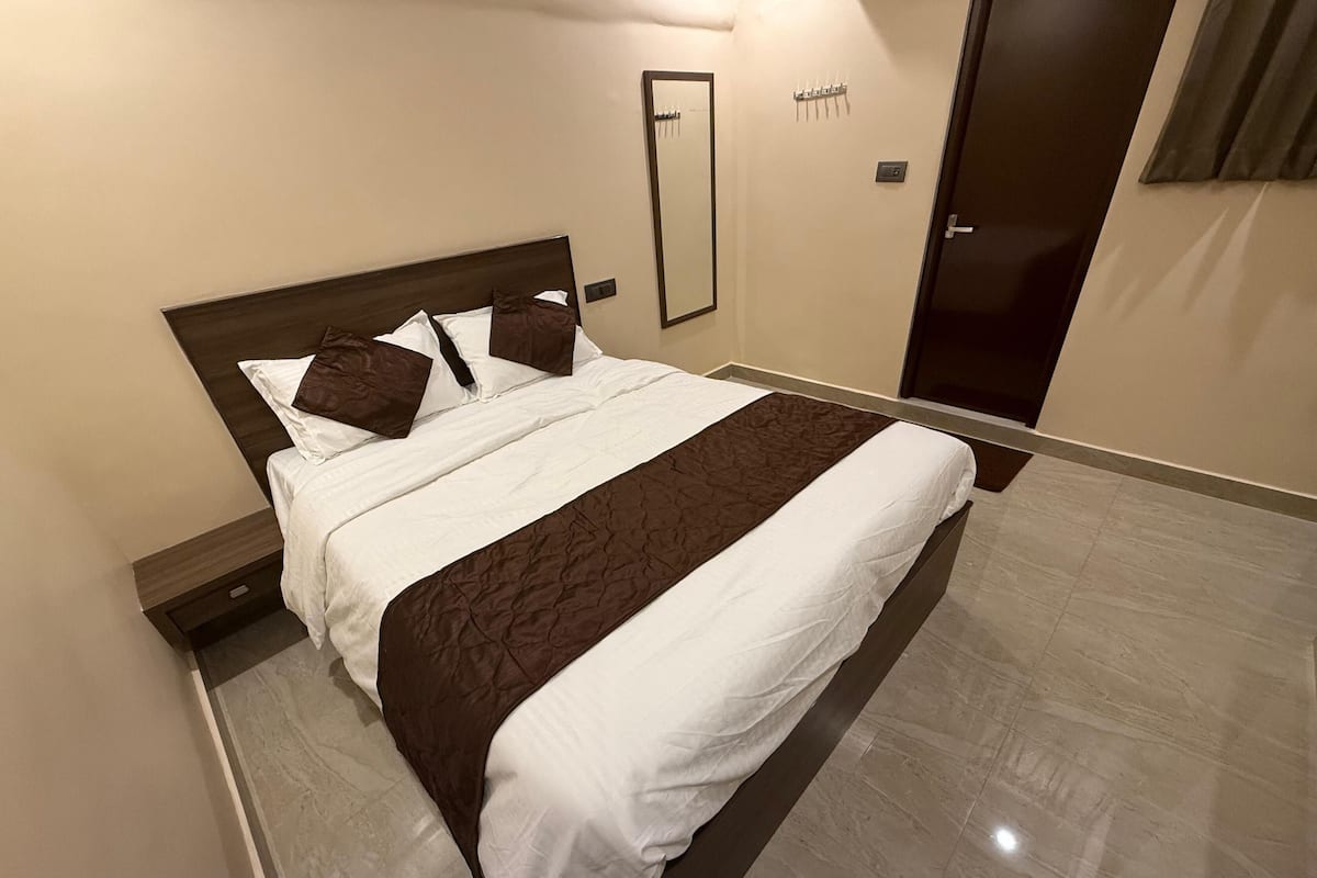 A neatly made bed with white and brown bedding, a wooden headboard, and a marble floor.