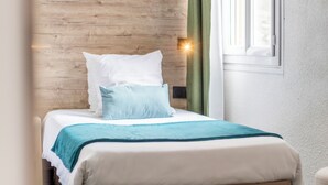 Ein ordentlich bezogenes Bett mit Holz Kopfteil, einem grünen Vorhang und einem Fenster mit Tageslicht.