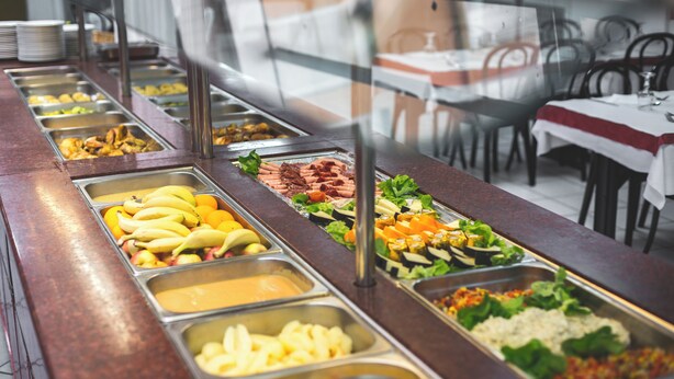 Ein reichhaltiges Buffet mit verschiedenen Speisen und ein Essbereich mit Tischen und Stühlen.