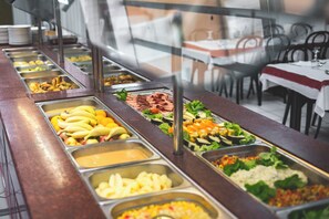 A buffet with various food items and a dining area with tables and chairs. - Hotel Estival-Arriel (Lourdes)
