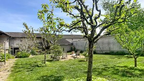 A well-maintained backyard with a lawn, a tree, and a patio area with outdoor furniture.