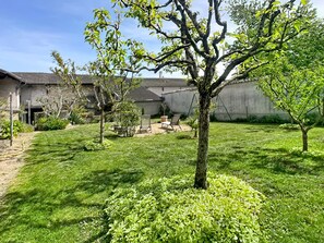 A well-maintained backyard with a lawn, a tree, and a patio area with outdoor furniture.