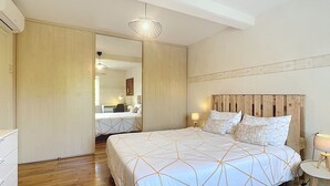 A bedroom with a large bed, wooden headboard, bedside lamps, and a mirror.