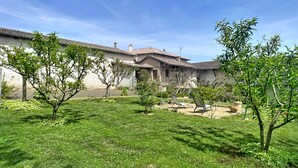A courtyard with a building featuring a tiled roof, a small fountain, and a few trees.