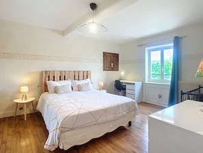 A bedroom with a bed, bedside tables, a desk, a chair, a window with curtains, and a radiator. - Gîte Fleurs de Gamay, in the heart of the Beaujolais region. Pets allowed (Lancié)