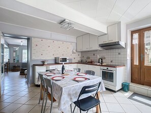 A modern kitchen with white cabinets, a dining table set for four, and a large window. - Gîte Fleurs de Gamay, in the heart of the Beaujolais region. Pets allowed (Lancié)