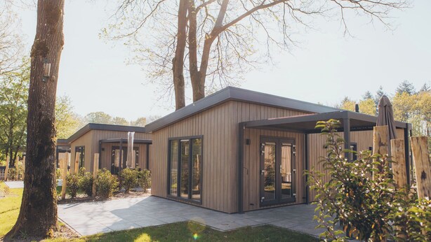 Een modern gebouw met grote ramen en een overdekt terras.