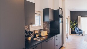 Een moderne keuken met een zwart aanrecht, een roestvrijstalen spoelbak en een messenblok.