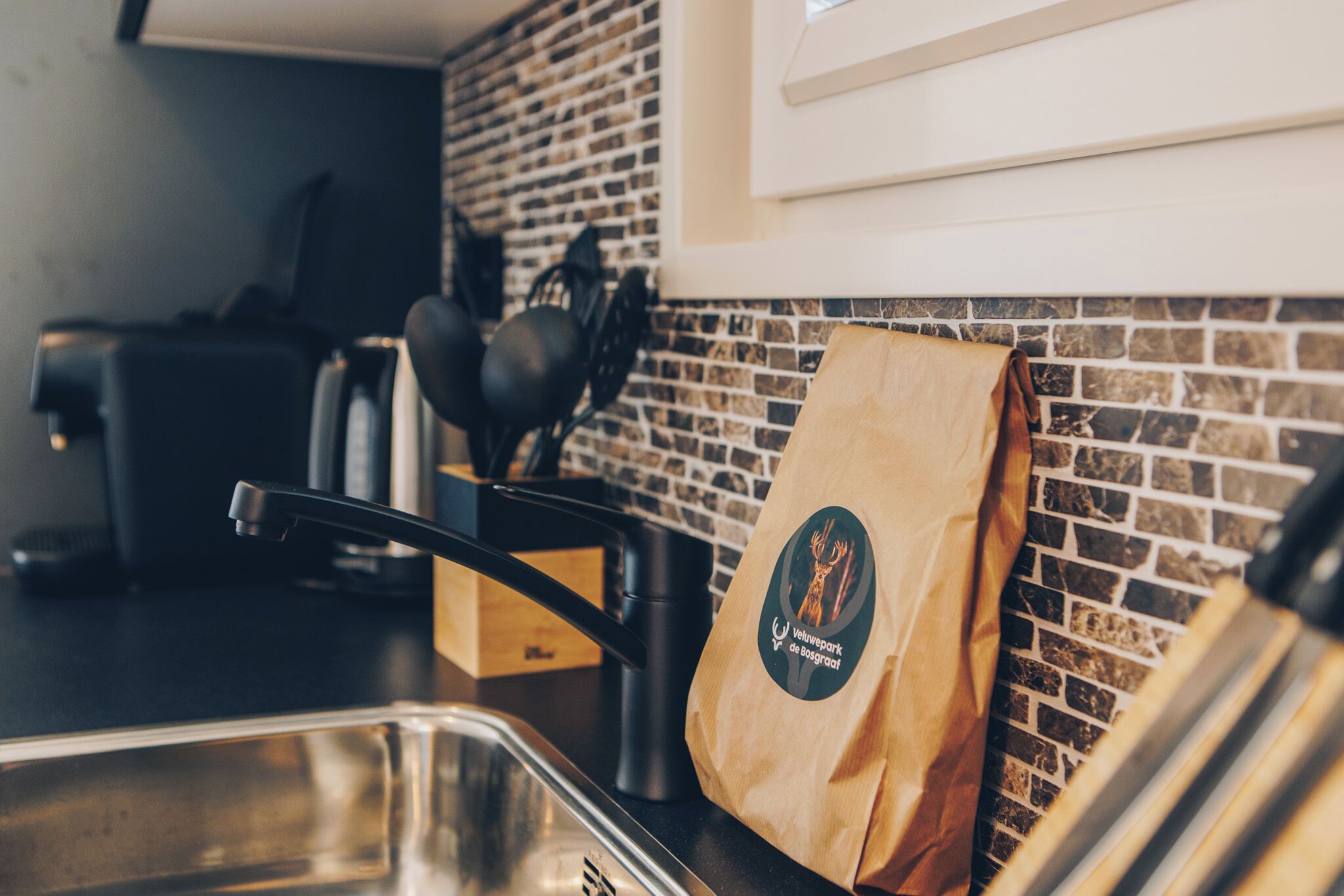 Un comptoir de cuisine avec un sac en papier, une machine à café et un évier.