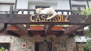 Un edificio de piedra con un letrero de madera que dice 'CASAROLZ' y un gato blanco sentado encima.