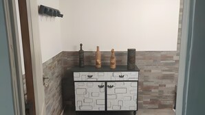 Una habitación con un armario blanco con cajones, piso de baldosas y una pared con textura.