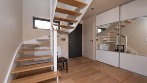 A modern interior with a wooden staircase, a small table, and a door. - Maison Desmathi: terrace with jacuzzi, garden, in Saint-Pierre-Quiberon (Saint-Pierre-Quiberon)