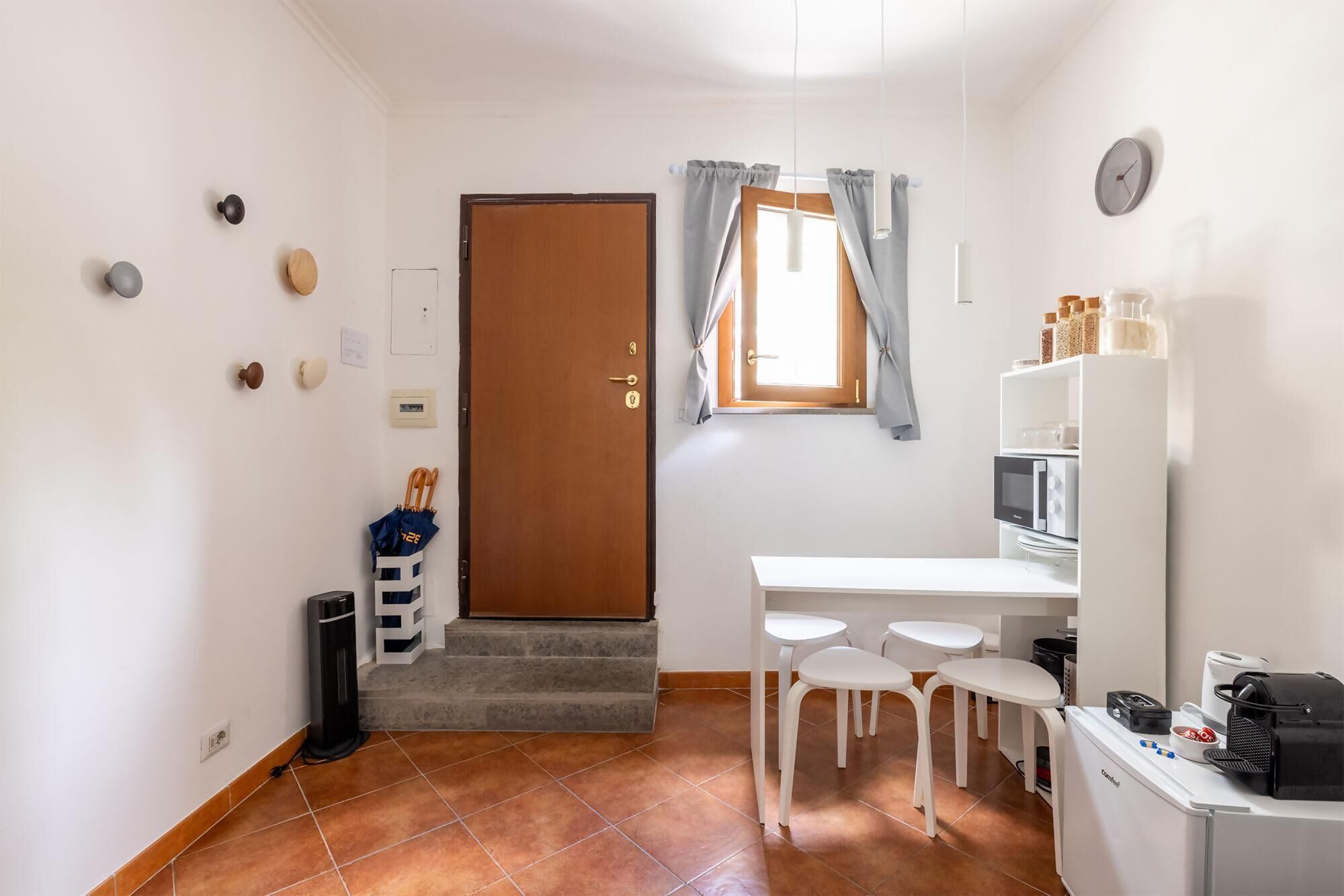 A compact kitchen with a white countertop, a microwave, a coffee machine, and a small refrigerator.
