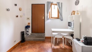 A compact kitchen with a white countertop, a microwave, a coffee machine, and a small refrigerator. - The Little House on Sannio Street (Roma)