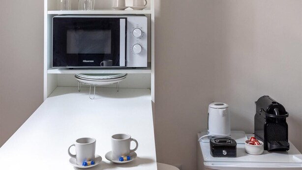 A kitchenette with a microwave, coffee maker, and storage shelves. - The Little House on Sannio Street (Roma)