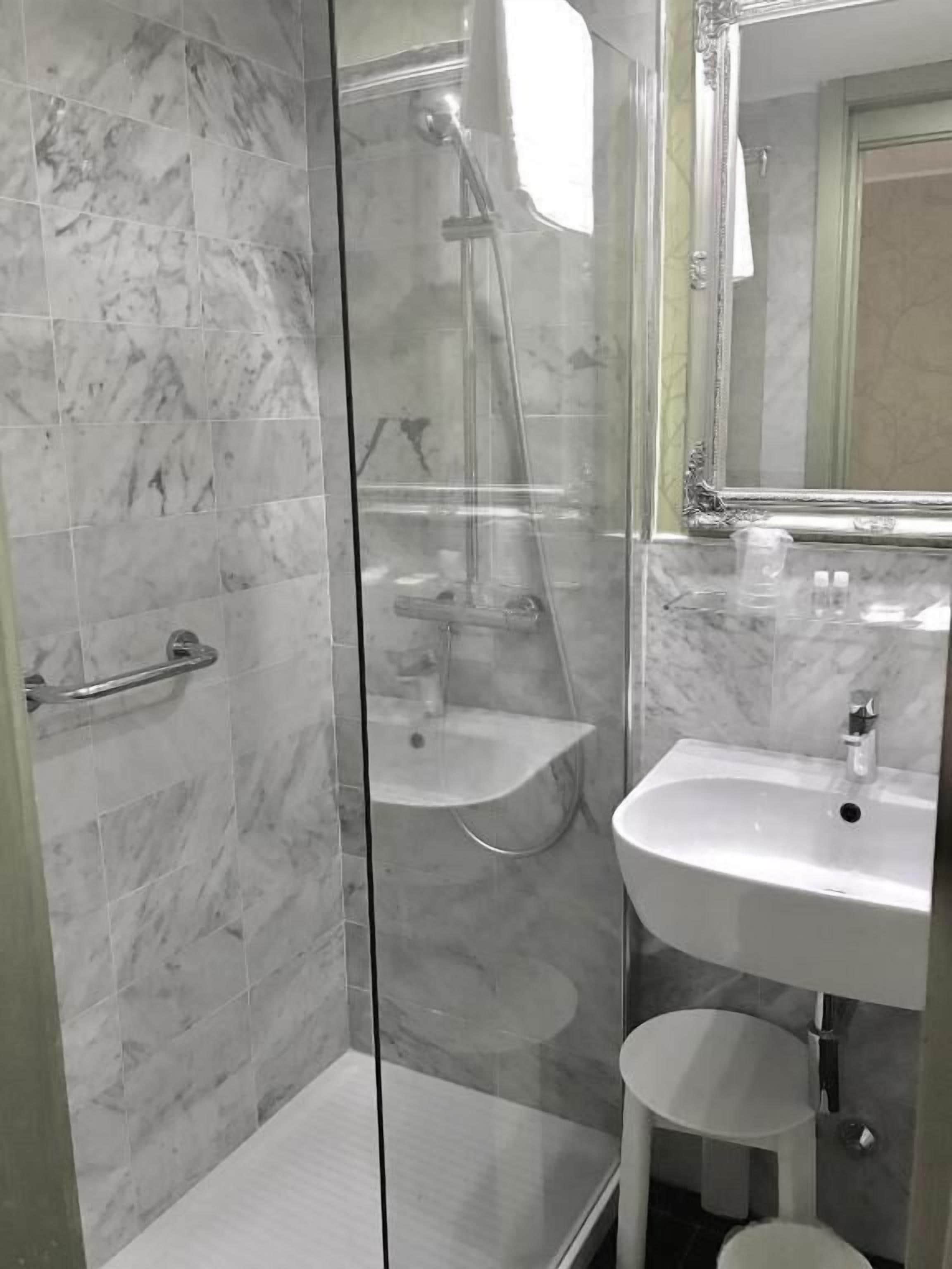 A bathroom with a glass-enclosed shower, a white sink, and a mirror above the sink.