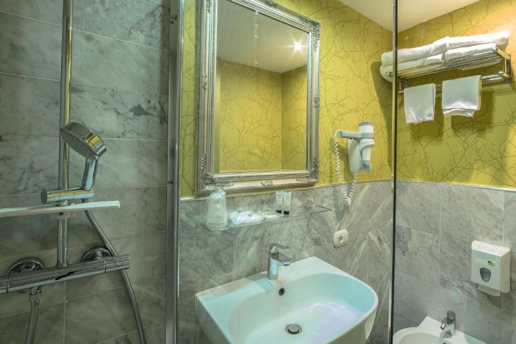 A bathroom with a marble sink, a large mirror, and a glass shower enclosure.