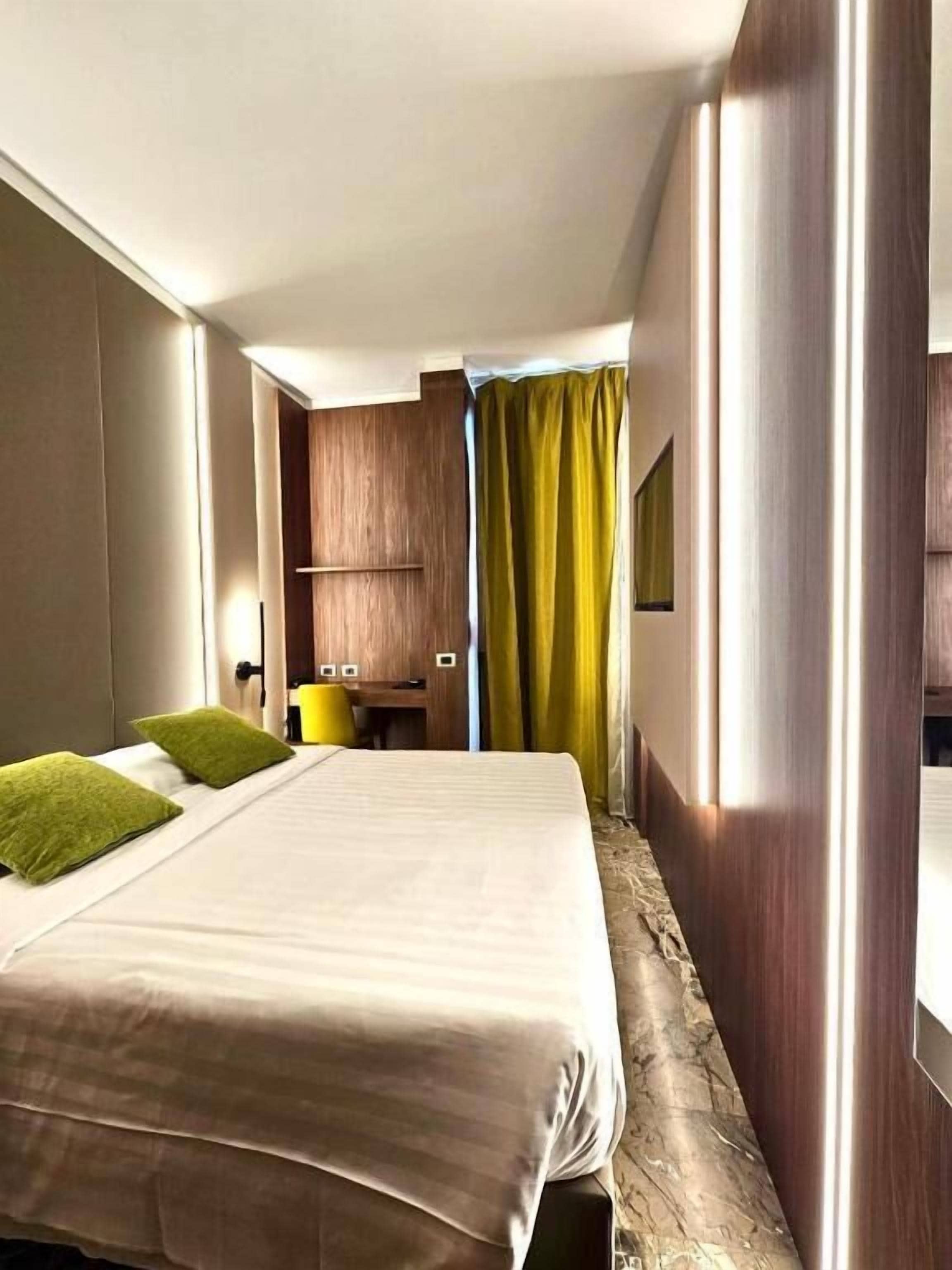 Quarto de hotel com uma cama grande, uma escrivaninha e uma cadeira.