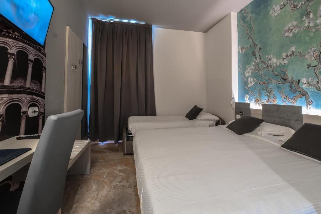 Habitación de hotel con dos camas, un escritorio y un televisor.