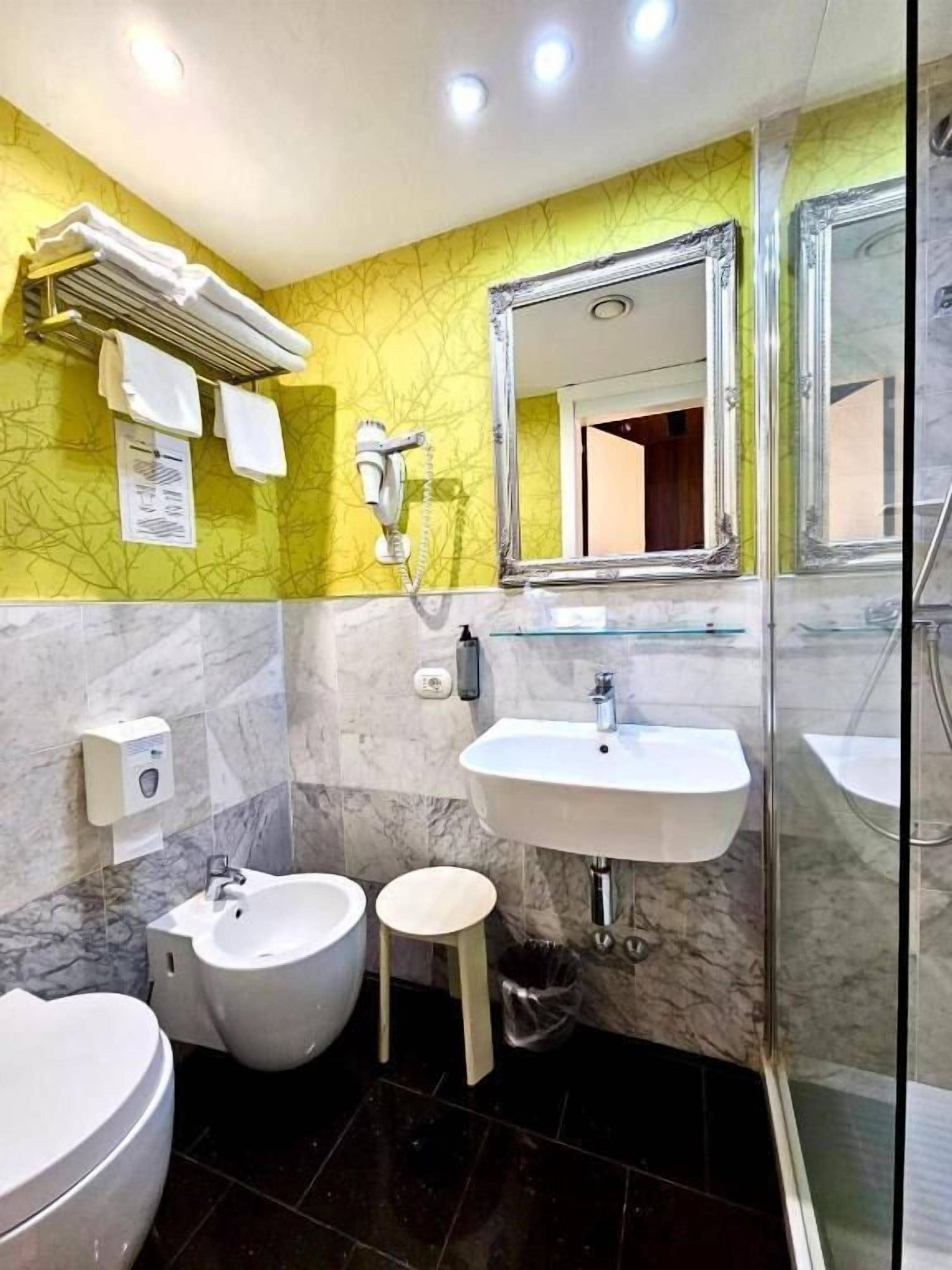 Een badkamer met een marmeren wastafel, een bidet, een toilet en een douche.