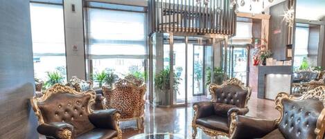 A lobby with ornate furniture, a glass coffee table, and a chandelier.