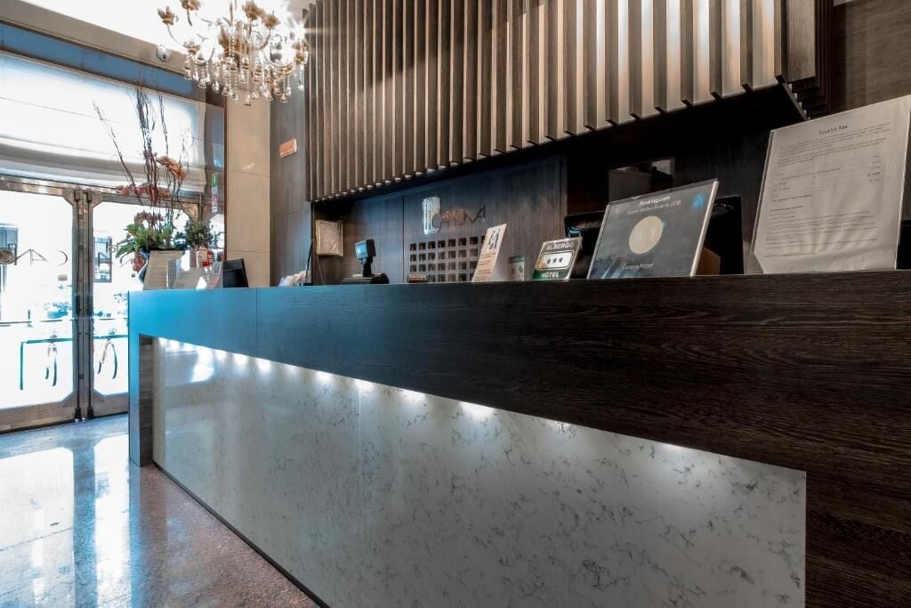 Un comptoir d’accueil d’hôtel avec un revêtement en marbre, un écran numérique et un panneau indiquant une réduction de 44 %.