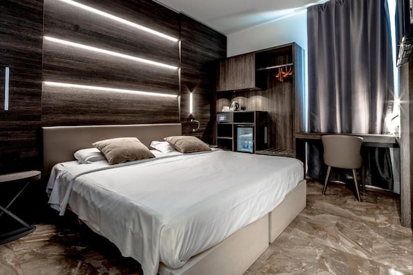 A modern bedroom with a large bed, a desk, and a wardrobe.