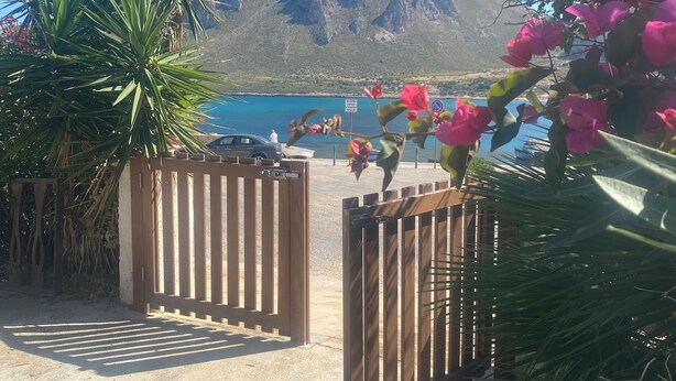 A wooden gate leading to a beach area with a mountain in the background.