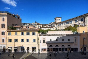 A historic square with traditional European architecture, including a prominent building with a clock tower and a central open space with shops. - LVD Lucina Luxury Apartament al Centro di Roma (Rome)