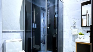 Un bagno moderno con cabina doccia in vetro, un water e un lavandino con specchio.