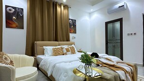 Una camera da letto moderna con un letto, una sedia, un comodino e una pianta decorativa.
