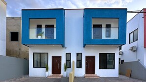Un edificio moderno di due piani con facciata simmetrica, caratterizzato da un ingresso centrale affiancato da finestre e porte.