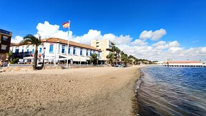 Hotel a primera línia de platja, amb sorra, palmeres i una bandera.