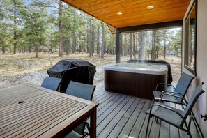 Une terrasse extérieure avec un jacuzzi, une plateforme en bois et des chaises.