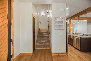 Eine Treppe führt zu einer Küche mit Holzboden und Pendelleuchten.